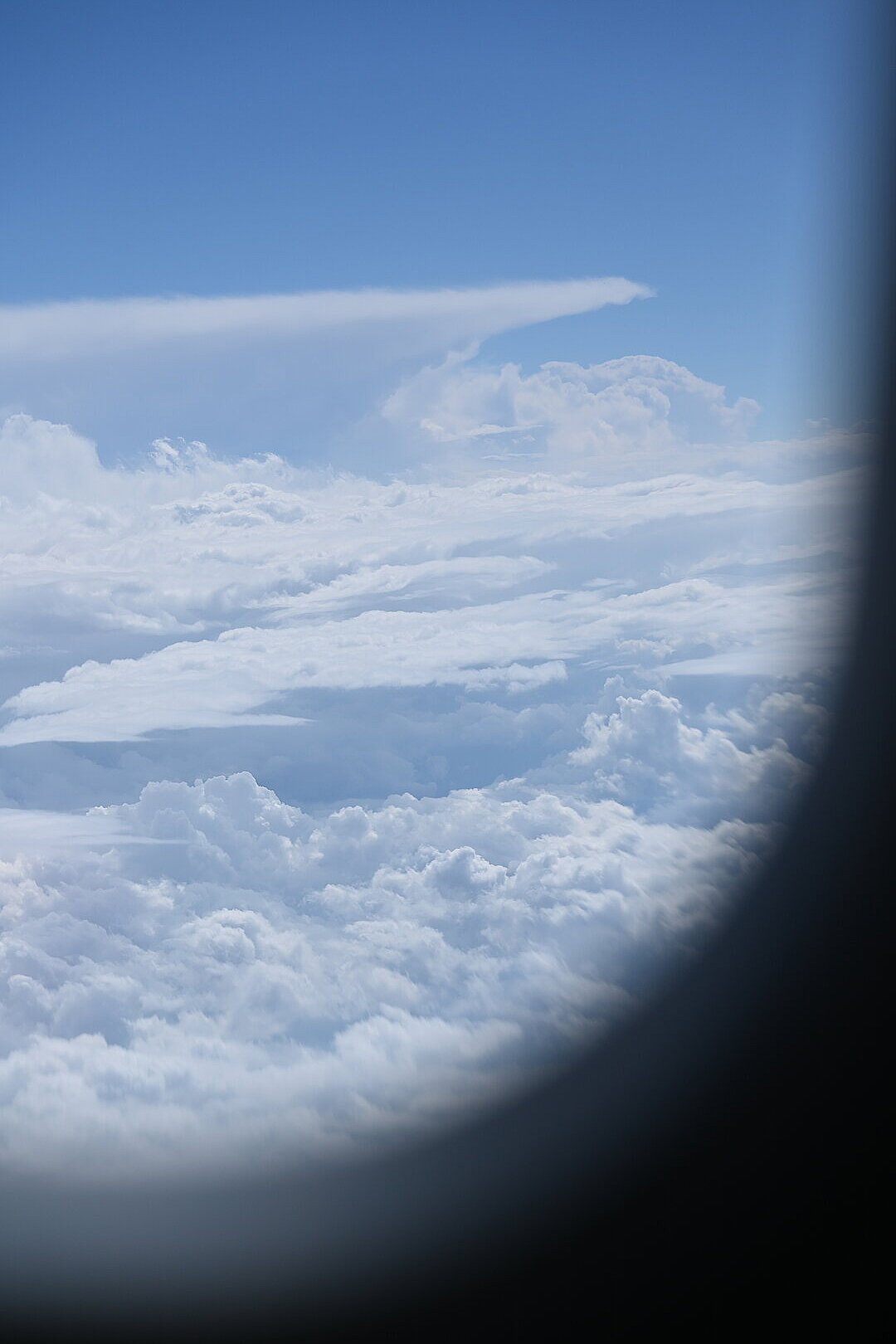 Blick aus dem Flugzeug auf Wolken unter einem blauen Himmel.