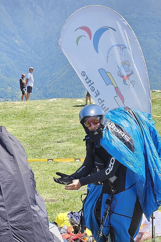 Pilotin steht im Gurtzeug und hält die Hände offen, während ein Schirm über ihr aufgespannt ist