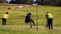 Gleitschirmflieger wird beim Punktlanden von zwei Juroren beobachtet