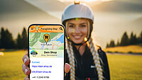 Frau mit Helm hält Smartphone mit Paragliding-Karten-App in die Kamera