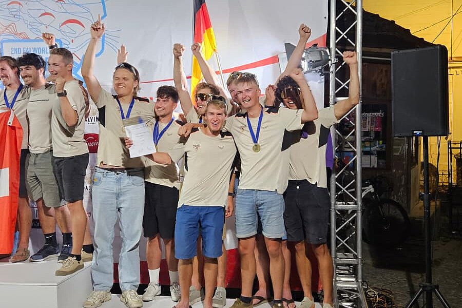 Gruppe junger Männer mit Medaillen jubelt auf einem Siegerpodest mit Platz 3 und Deutschlandflagge.