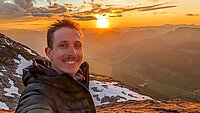 Selfie eines jungen Mannes bei Sonnenuntergang in den Bergen
