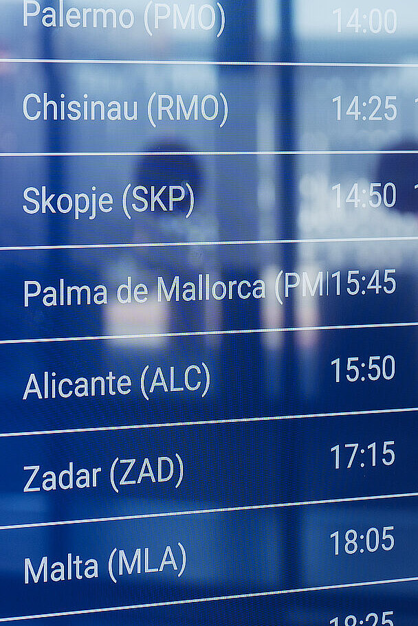Flughafentafel mit Flugzielen und Abflugzeiten, darunter Skopje, Palma de Mallorca und Zadar.