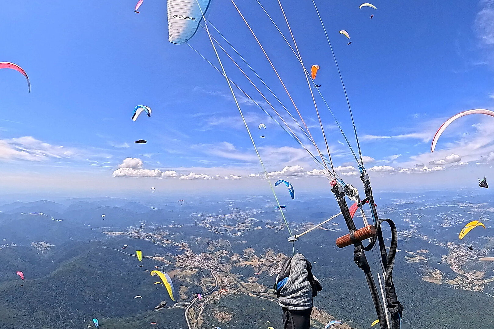Mehrere Gleitschirme fliegen über Bergen und einer weiten Landschaft