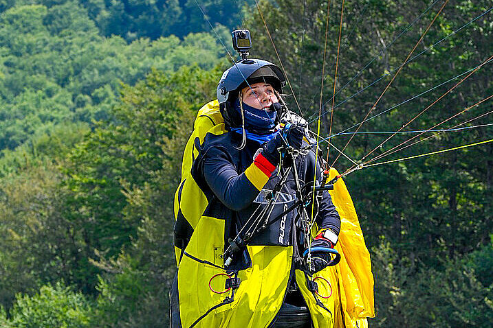 Pilotin mit Helm und Kamera läuft mit Ausrüstung.