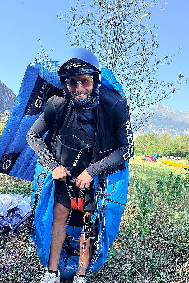 Ein Pilot lächelt beim Anziehen seines Gurtzeugs am Startplatz.
