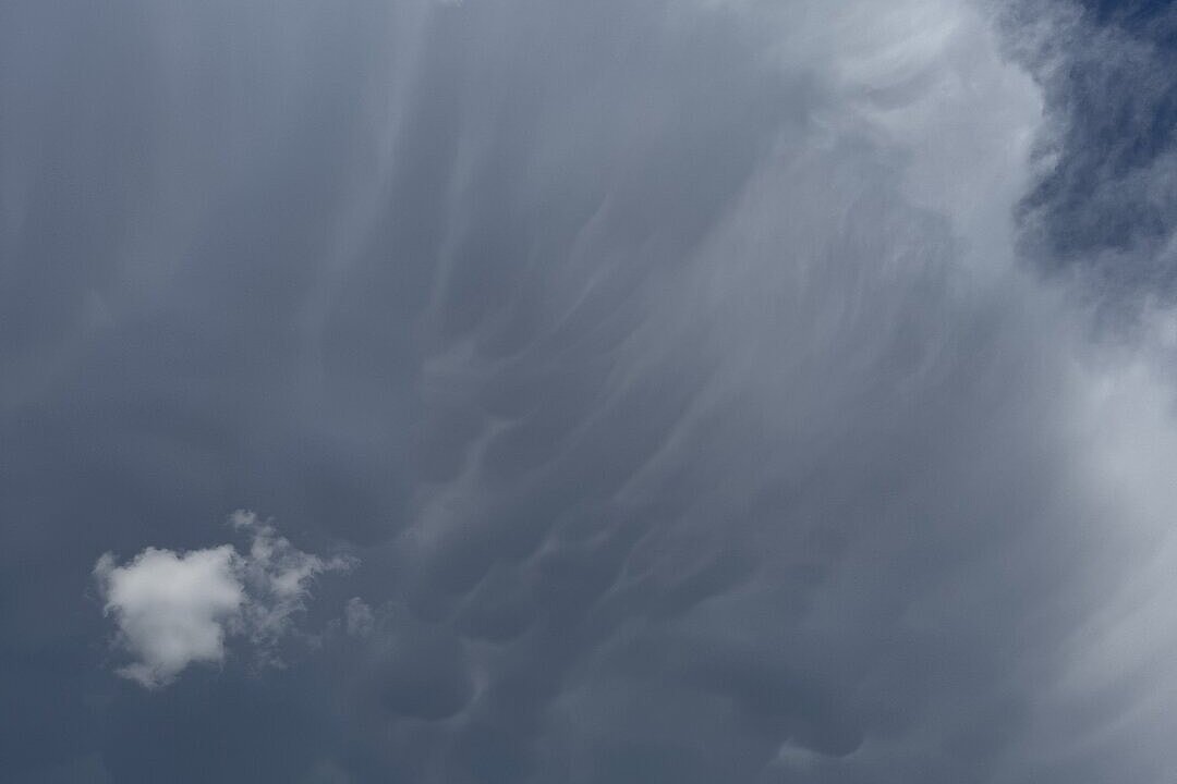 Große, faserige Wolken am Himmel vor blauem Hintergrund.