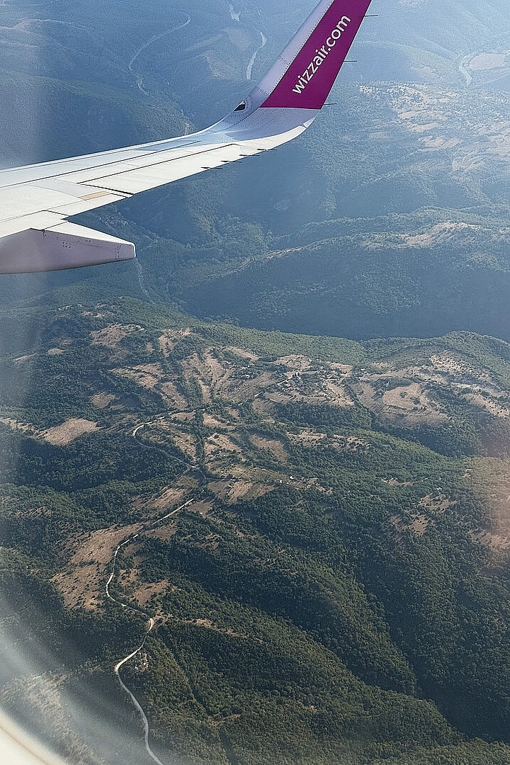 Blick aus dem Flugzeug auf Gebirge und Täler unter dem Flügel.