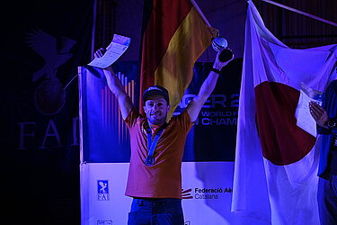 Triumphierender Pilot mit Pokal, Urkunde und Medaille um den Hals