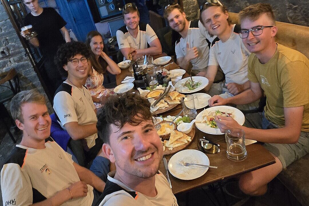 Eine Gruppe von Personen sitzt an einem Tisch in einem Restaurant und isst gemeinsam.