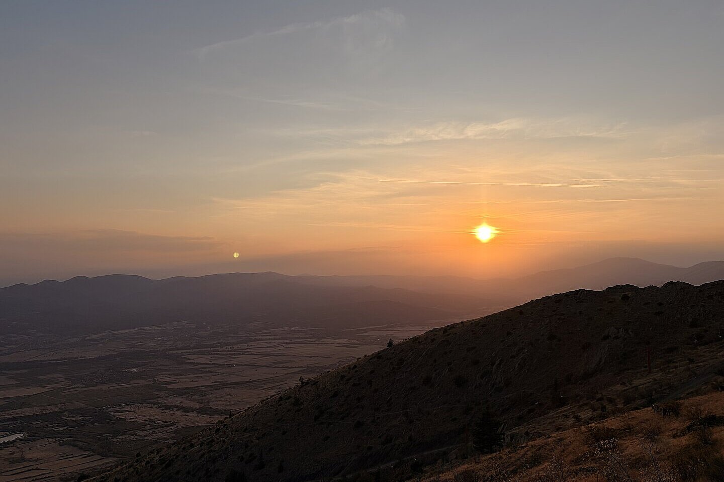 Sonnenuntergang über Hügeln und einem Tal.