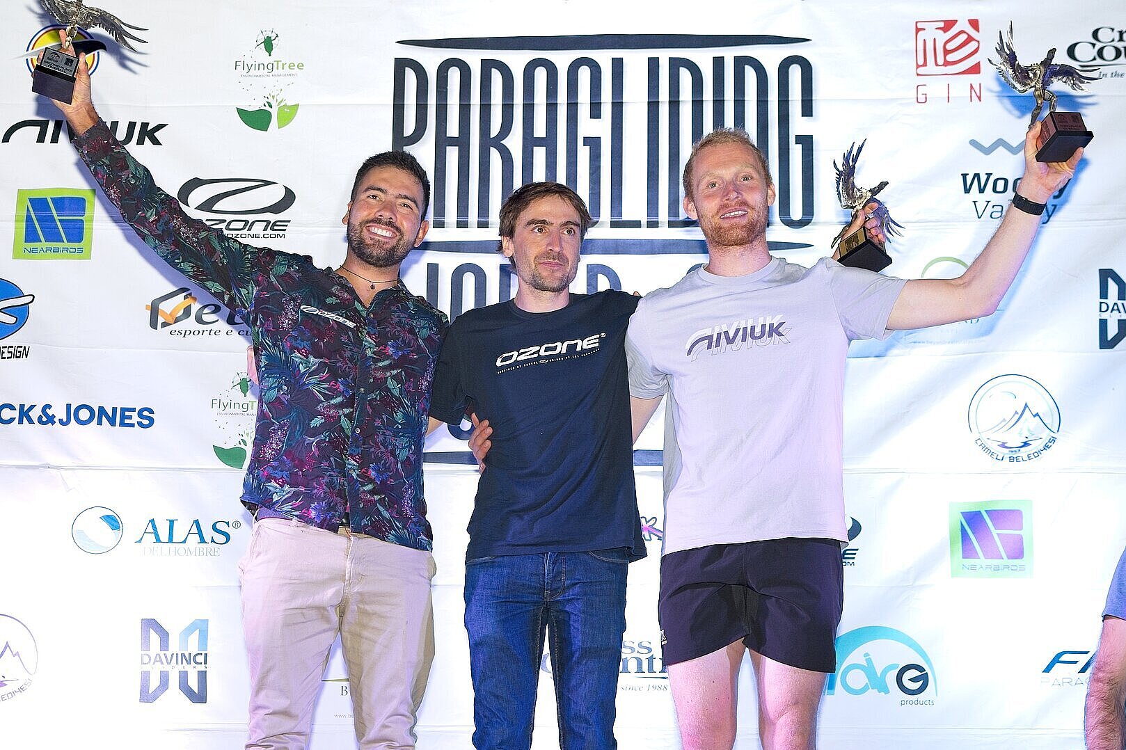 Glückliche Gewinner posieren stolz mit Trophäen vor Eventbanner