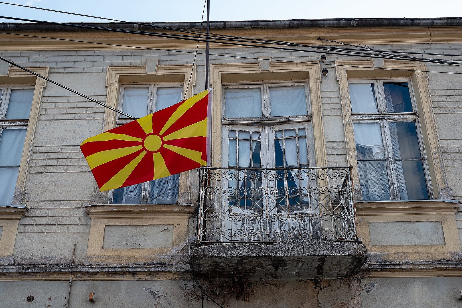 Nordmazedonische Flagge hängt vor einem alten Gebäude mit Balkon