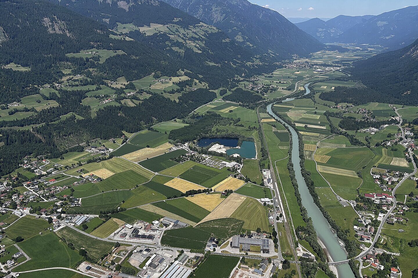 Blick aus der Luft über ein Tal mit Fluss, Feldern, Straßen und verstreuten Ortschaften.