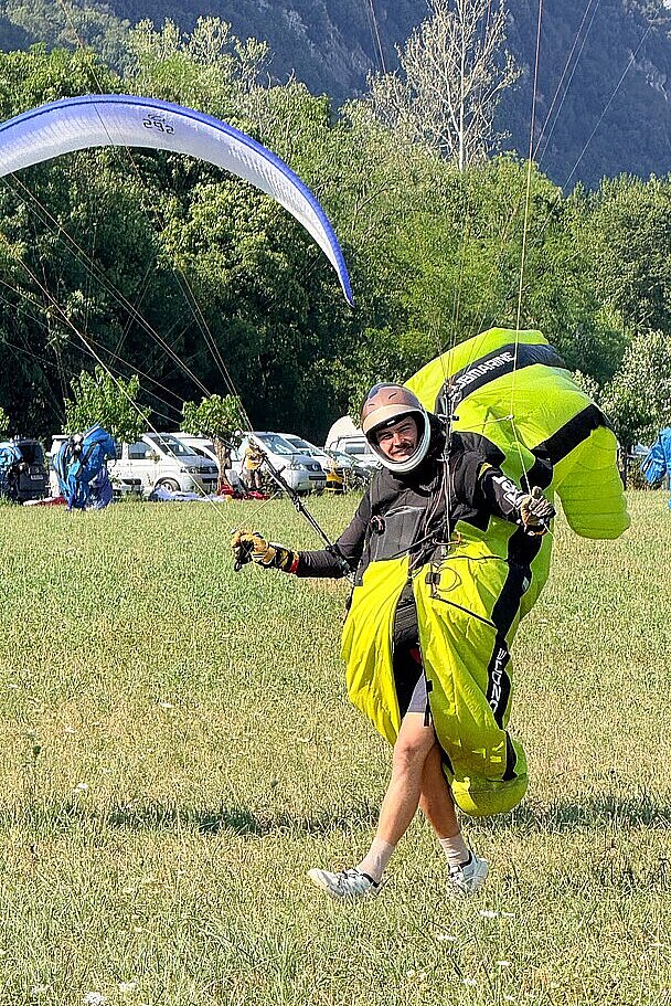 Ein Pilot läuft mit ausgelegtem Schirm über eine Wiese.