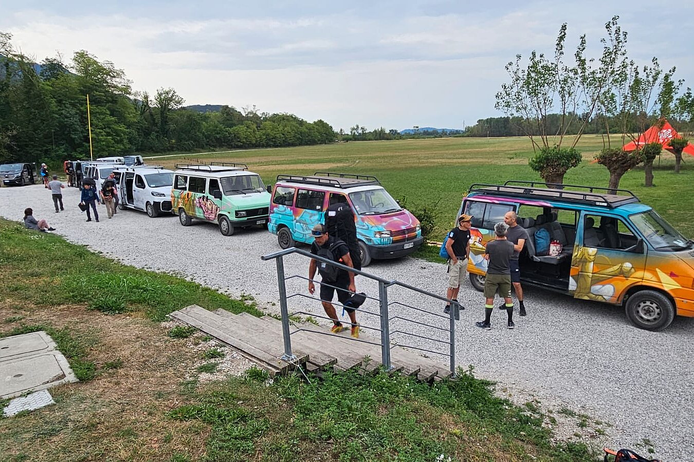 Mehrere Vans stehen an einem Feldweg, daneben laufen und stehen Personen mit Ausrüstung.