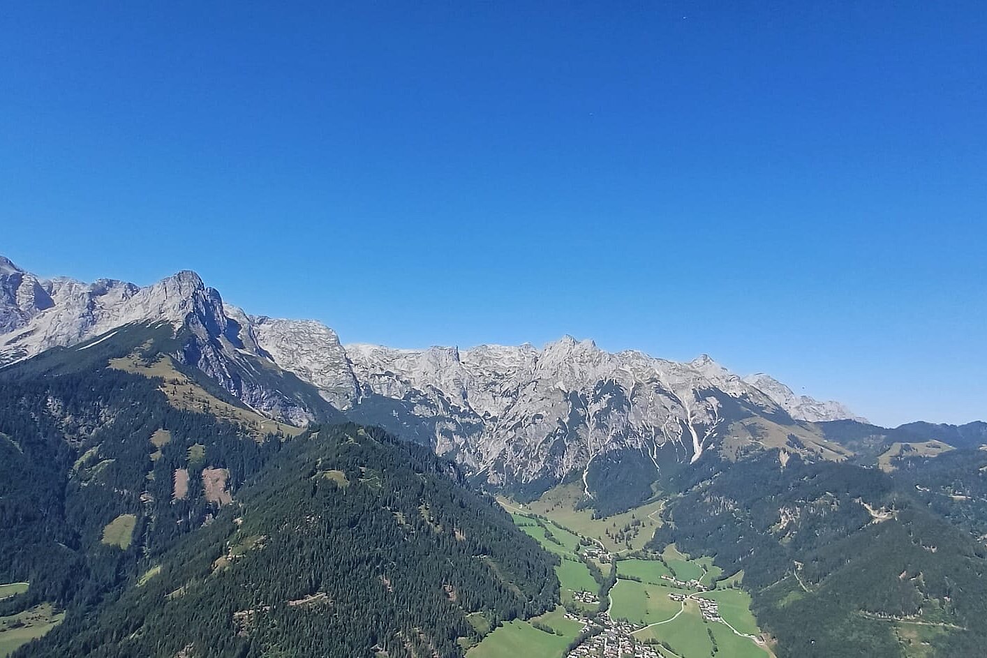 Berglandschaft mit schroffen Felswänden, grünen Tälern und blauem Himmel