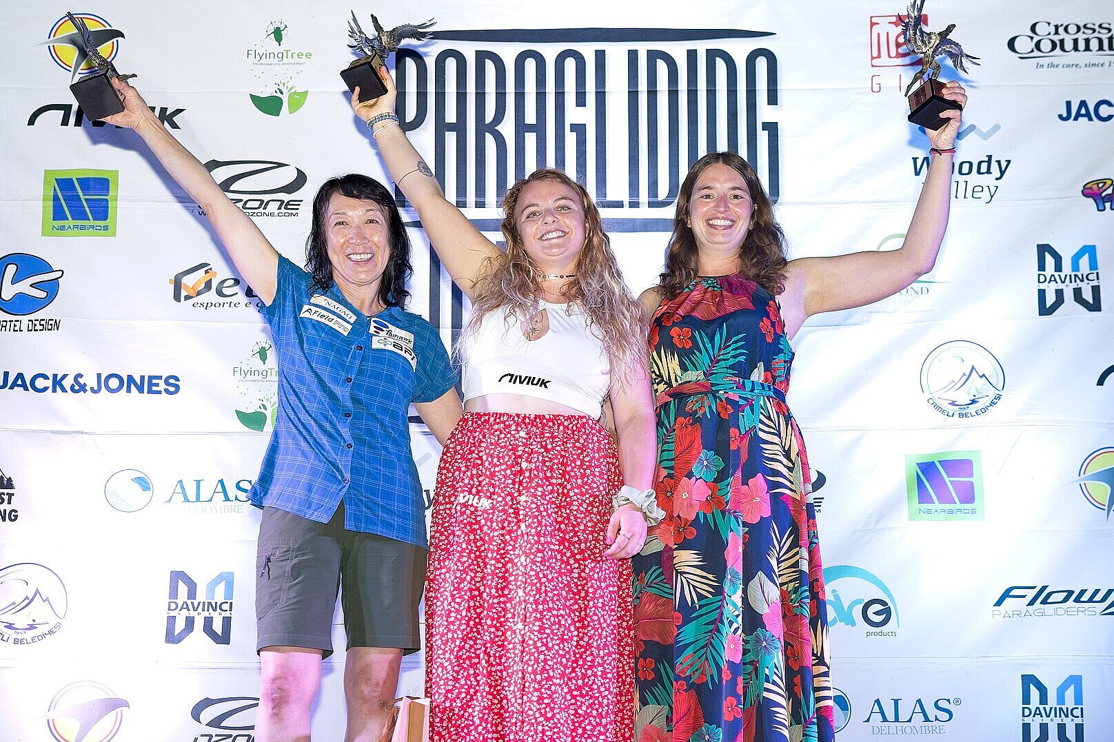 Glückliche Gewinnerinnen posieren stolz mit Trophäen vor Eventbanner