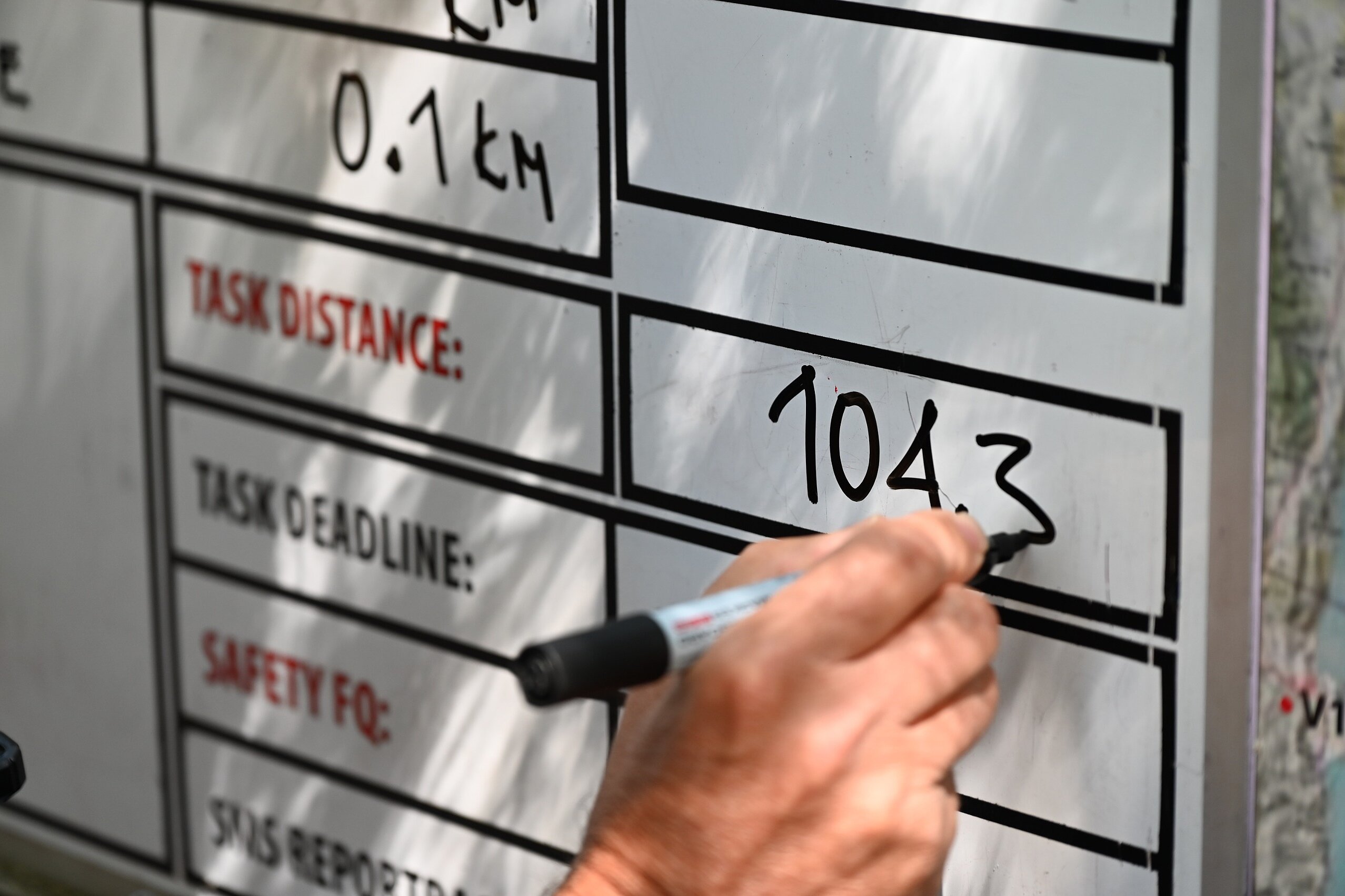 Eine Hand schreibt 104,3 in ein Task-Board.